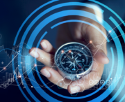 A hand holds a compass surrounded by digital graphics of charts, graphs, and circular interface elements, suggesting technology and navigation concepts.