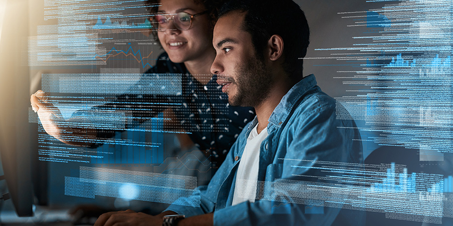 Two people look at a computer screen with digital data graphics overlaid, collaborating and discussing information in a modern workspace.