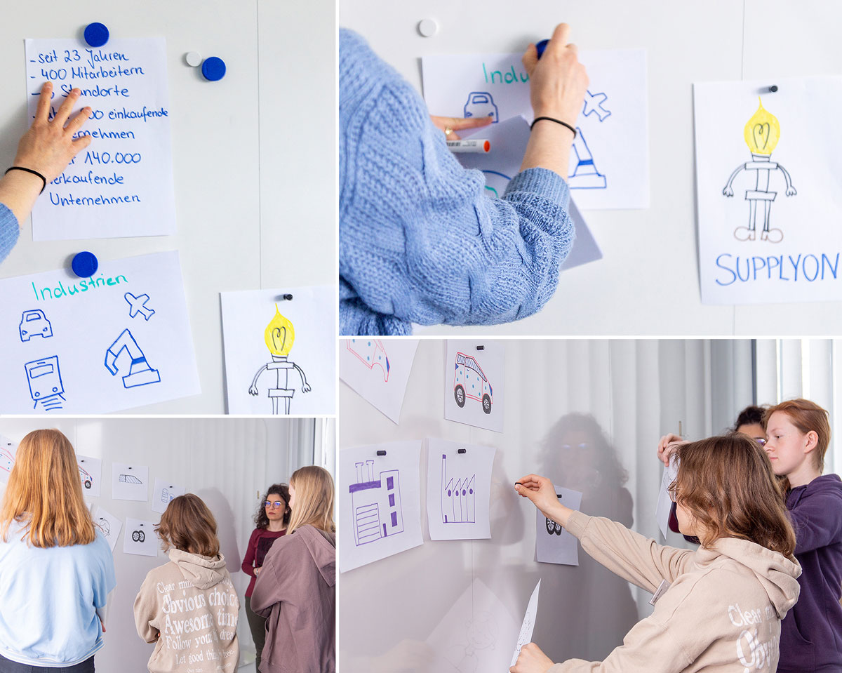People are pinning and discussing hand-drawn posters with industrial themes on a whiteboard in a bright room, celebrating Girls Day and inspiring creativity.